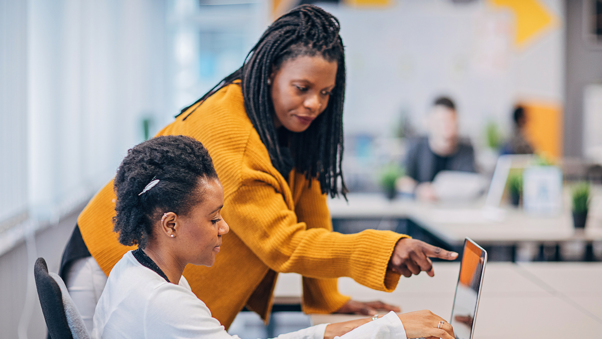 An older black woman showing a younger black woman something on the screen